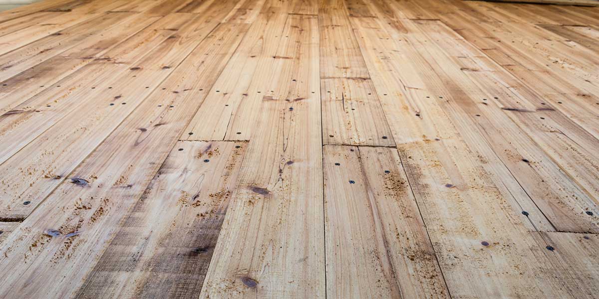 An angled view of weathered hardwood floor planks, illustrating whether wood flooring can be successfully repaired after sustaining water damage.