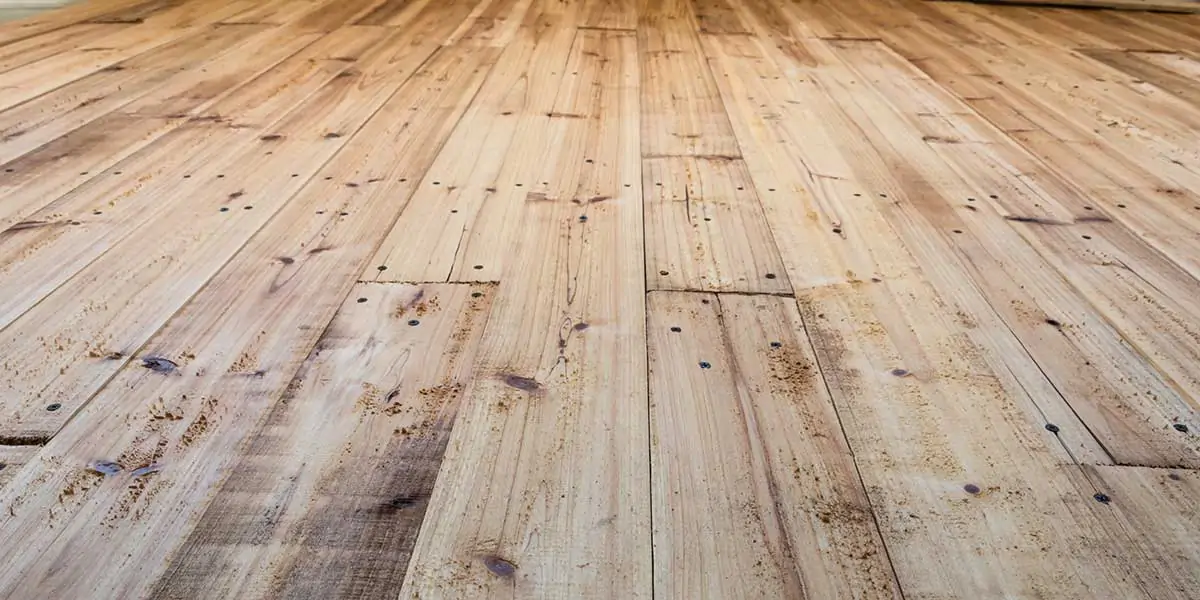 An angled view of weathered hardwood floor planks, illustrating whether wood flooring can be successfully repaired after sustaining water damage.